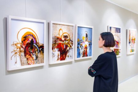 01 In a art gallery young woman visits an art exhibition and watches artist's collection.